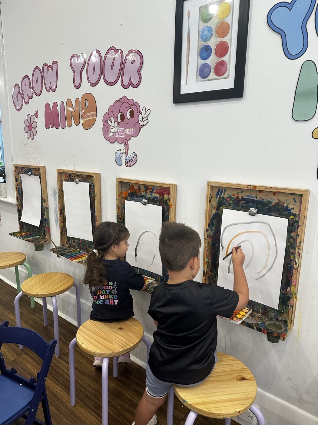 Two children painting at wall easels under the Grow Your Mind display at Mini Ivy Adelaide