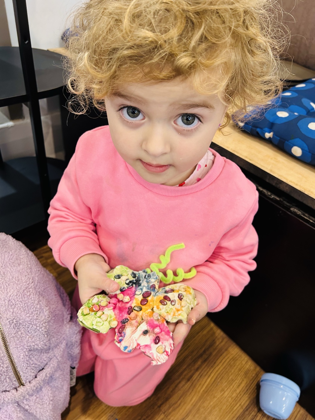 Little girl proudly holding the seed butterfly she made at a Mini Ivy party