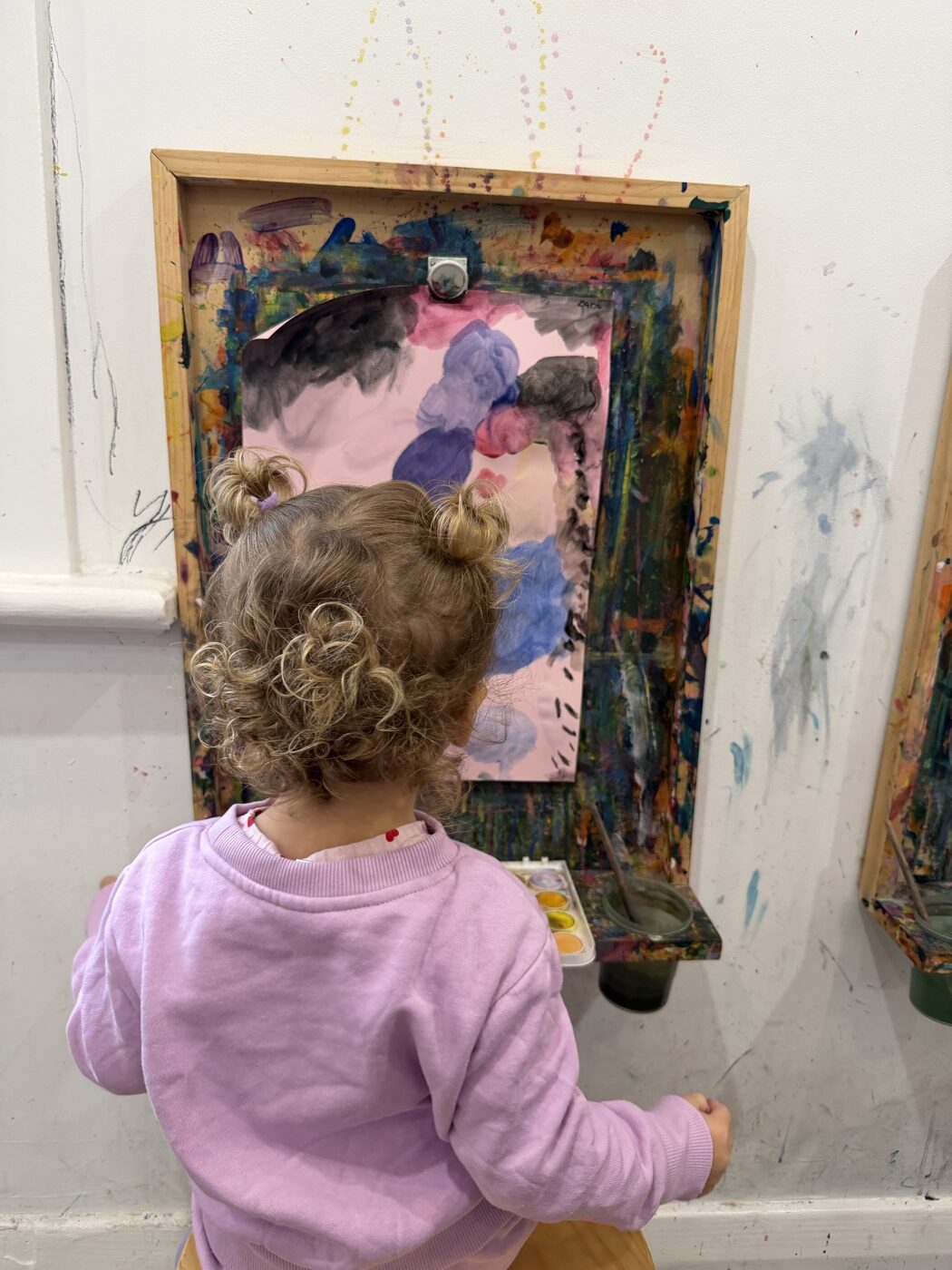 Child painting at a wall easel at Mini Ivy, near Grange
