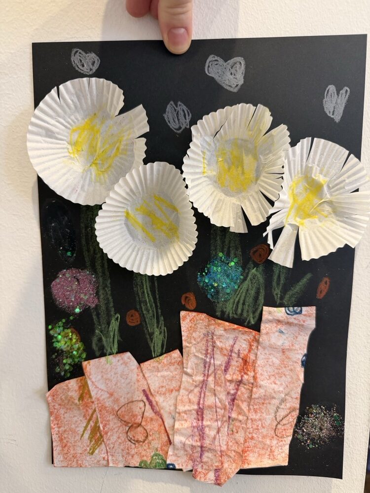 Flowers made from cupcake liners on black paper with painted stems